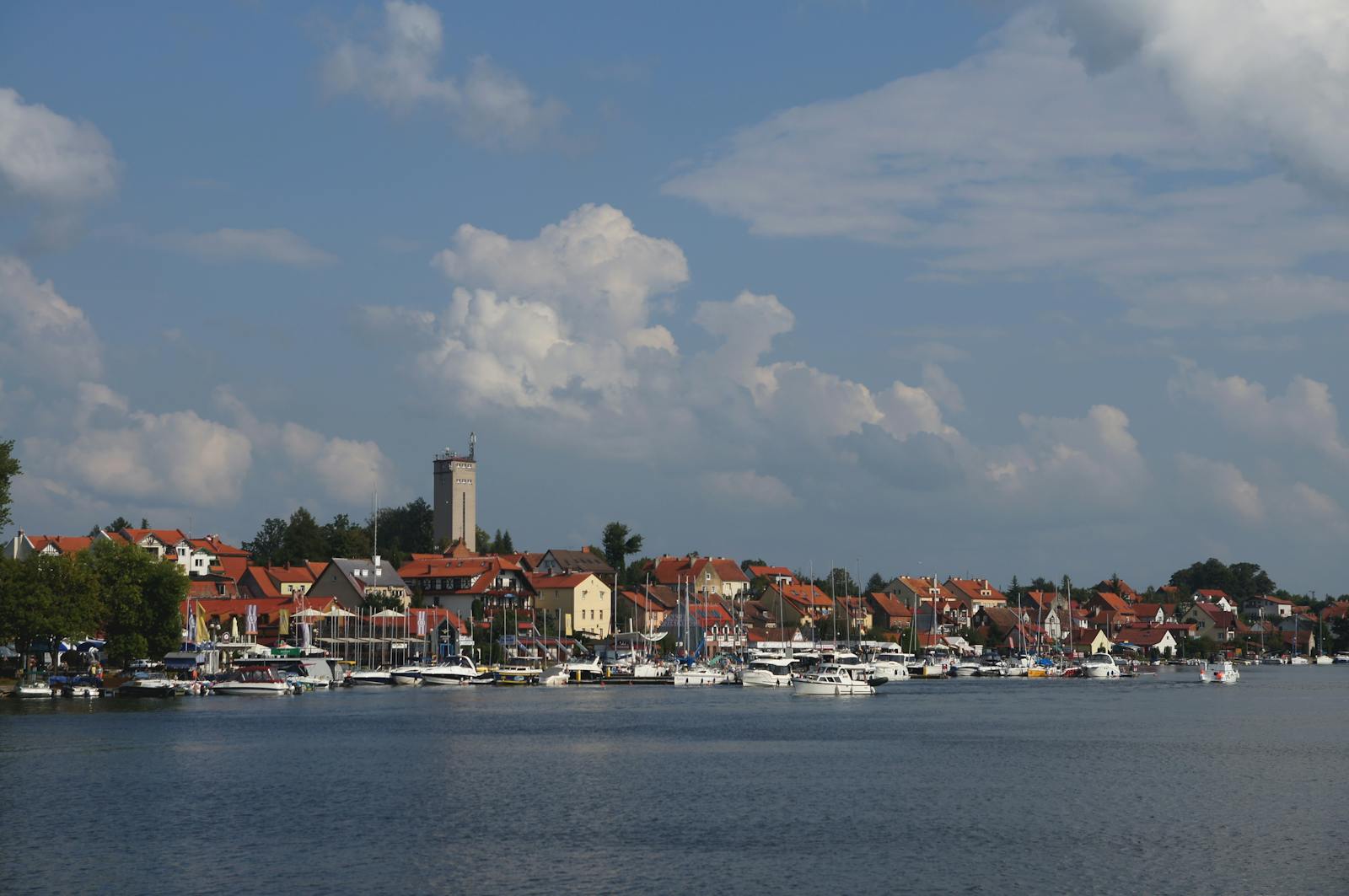 Picturesque view of Augustów with boats docked by the waterfront under a blue sky.