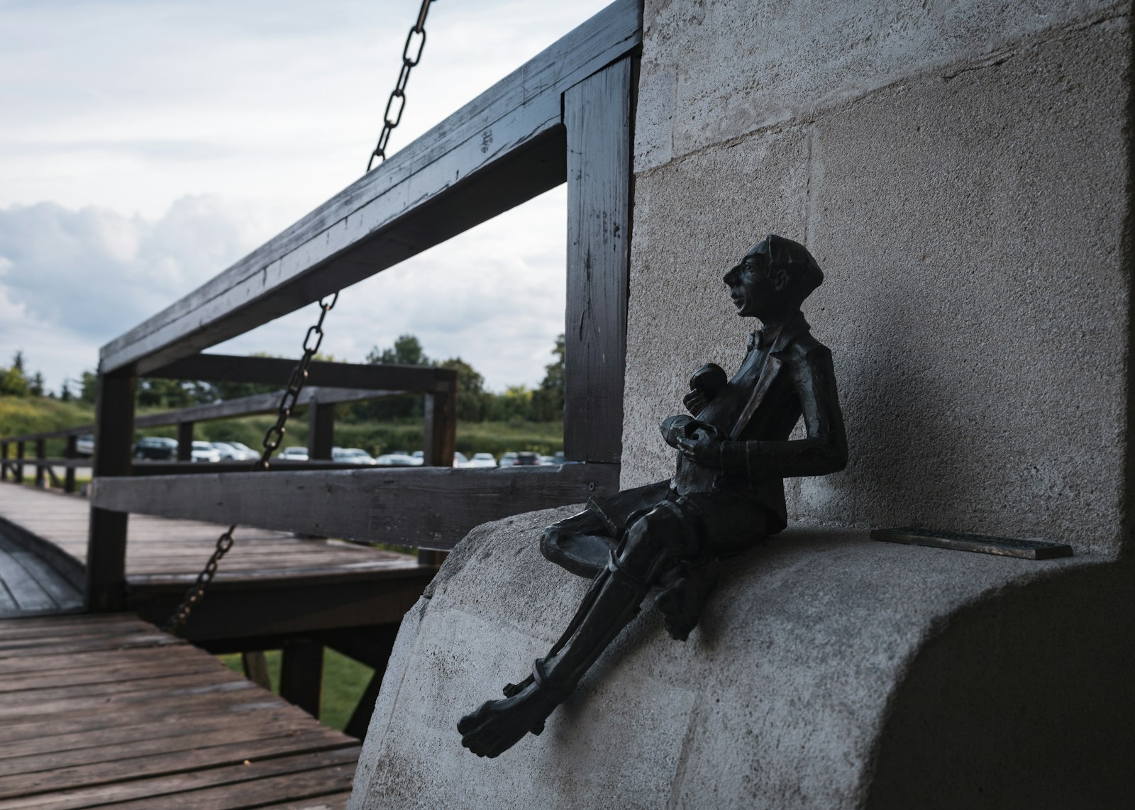 A statue of a man sitting on a cement wall