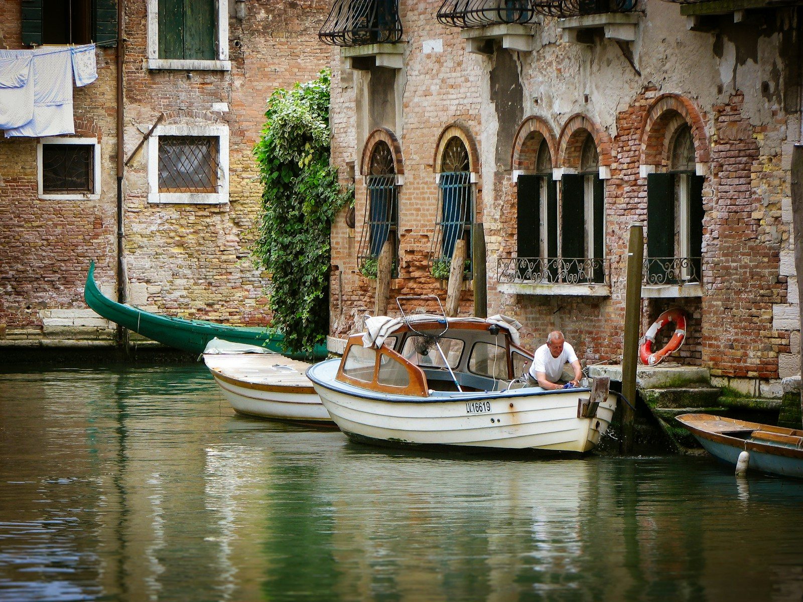 Man working on a boat by a canal in venice